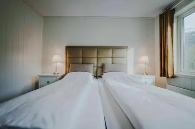 two white beds in a bedroom with two lamps at Loen Apartments in Loen