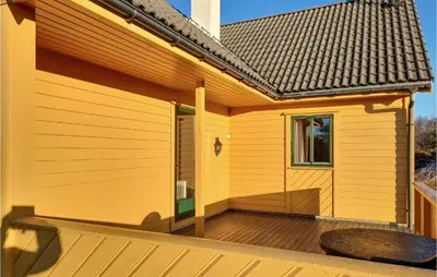 a yellow house with a wooden deck at 4 Bedroom Stunning Home In Auklandshamn in Tjernagel