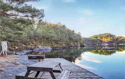 a wooden bench sitting on a dock next to a lake at 4 Bedroom Lovely Home In Nordtveitgrend in Hjartåker