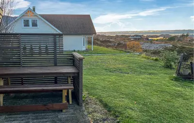 a wooden bench in front of a house at Cozy Home In Vevang With Sauna in Vevang