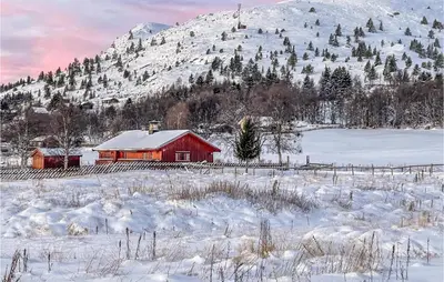 a red barn in a snowy field with a mountain at 3 Bedroom Lovely Home In Vinstra in Vinstra
