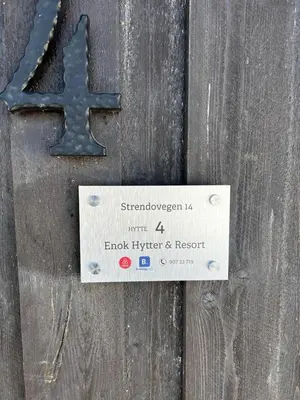 a sign on a wooden door with a cross on it at Enok Hytter & Resort in Liagardane