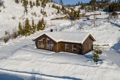 a log cabin in the snow with snow on the roof at Moderne ski-in & ski-out hytte i Valdres, Norge - alt inkludert for ditt fjelleventyr in Aurdal