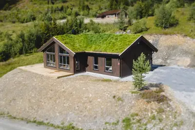 a small house with a grass roof on a hill at Moderne ski-in & ski-out hytte i Valdres, Norge - alt inkludert for ditt fjelleventyr in Aurdal