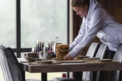 a woman standing over a table with food on it at Moderne ski-in & ski-out hytte i Valdres, Norge - alt inkludert for ditt fjelleventyr in Aurdal
