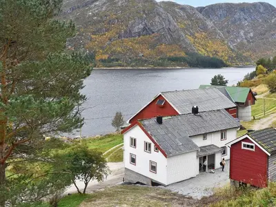 a group of red and white buildings next to a lake at 8 person holiday home in Snillfjord-By Traum in Snillfjord