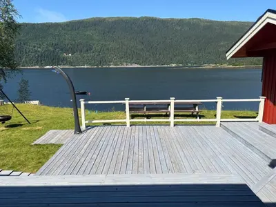a wooden deck with a bench overlooking a lake at 9 person holiday home in Mosvik-By Traum in Mosvik