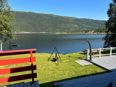 a bench and a swing on the grass near a lake at 9 person holiday home in Mosvik-By Traum in Mosvik