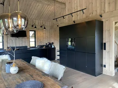 a living room with a table and a kitchen at Beautifully styled mountain lodge with high standards, 10 minutes from Geilo in Geilo
