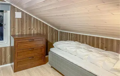 a bedroom with a bed and a wooden wall at 3 Bedroom Gorgeous Home In Brøttum