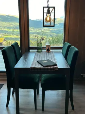 a dining room table with green chairs and a window at Vangslia, Oppdal. Lekker leilighet med ski inn/ski ut in Oppdal