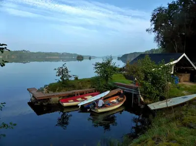 a group of boats are docked on a lake at Alone In The Woods With Your Own River Nearby in Fitjar