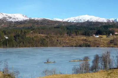 a large lake with snow covered mountains in the background at Alone In The Woods With Your Own River Nearby in Fitjar