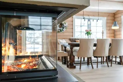 a fireplace in a living room with a table and chairs at Large and luxurious family cabin in Myrkdalen in Helgatun