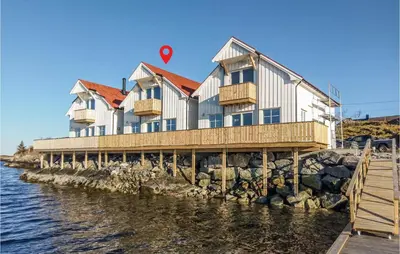 a building on a pier next to the water at Beach Front Home In Smøla With Kitchen in Smøla
