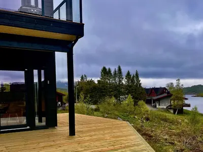 a house with a deck with a view of a lake at Fjellsætra Alpegrend in Sykkylven