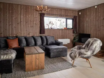 a living room with a black couch and a table at Fjellsætra Alpegrend in Sykkylven