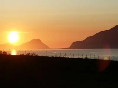 a sunset over the water with mountains in the background at Strøken leilighet in Åheim