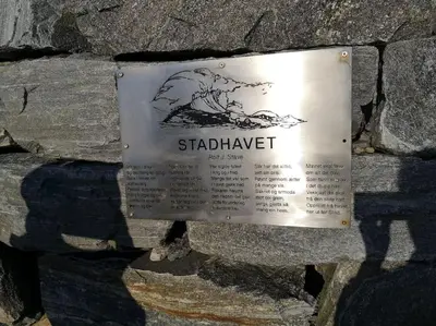 a sign on the side of a stone wall at Strøken leilighet in Åheim