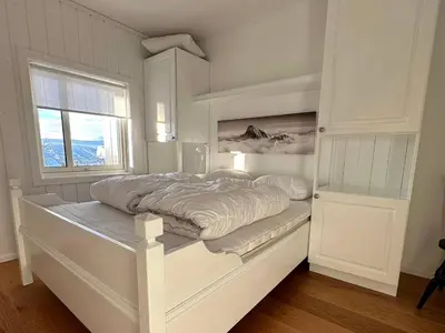 a white bed in a room with a window at Bjelbølens stjernely in Beitostøl