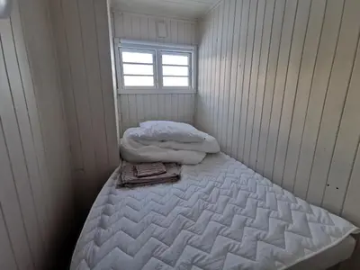 a small white room with a bed with a window at Tangen - cabin with 4 bedrooms - great nature in Norheimsund