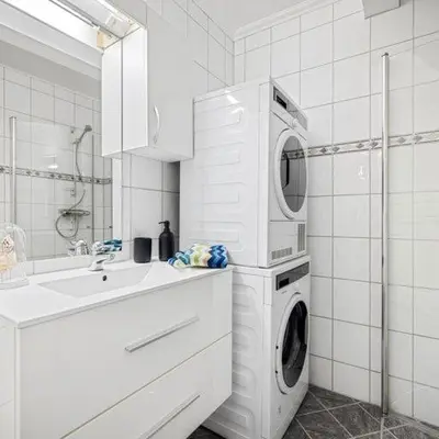 a white bathroom with a washing machine and a sink at Holmboe Apartment in Bergen