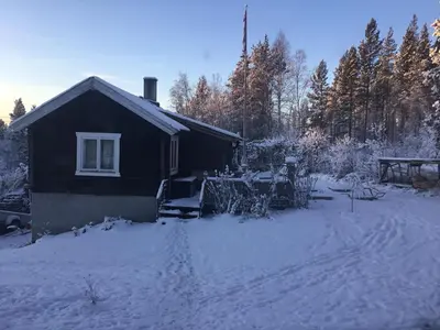 a house with snow on the ground next to a house at Furuly vakantiehuis in Vingelen
