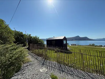 a fence next to a field with a shed at Kråen Gard in Larsnes