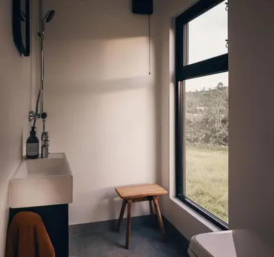 a bathroom with a window and a stool next to a sink at Kråen Gard in Larsnes