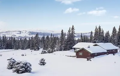 a cabin in the snow with trees and mountains at Cozy Home In Ulnes With Sauna in Ulnes
