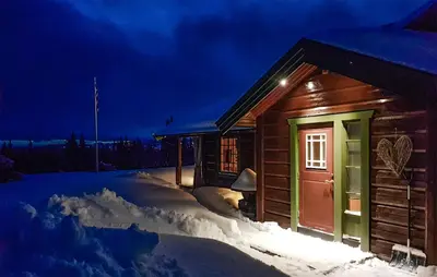 a log cabin in the snow at night at Cozy Home In Ulnes With Sauna in Ulnes
