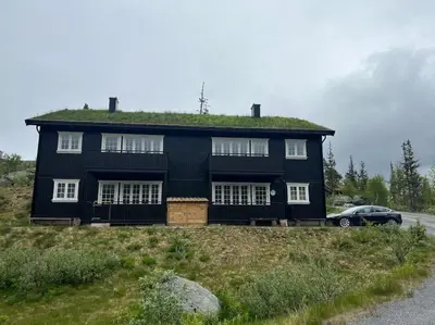a black house with a grass roof on a hill at Gaustablikk - ski in & out apartment - Mountain View in Gaustablikk