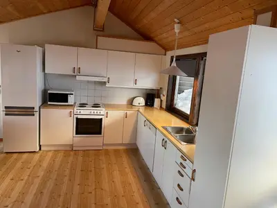 a kitchen with white appliances and a wooden floor at Fagertoppen 6B in Trysil