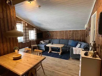 a living room with a blue couch and a table at Koselig hytte med uteplas ved Hallingdalselva in Ål