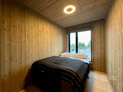 a bedroom with a bed in a wooden wall at Brand new cabin at Hovden cross-country skiing in Hovden