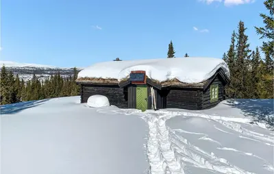 a snow covered cabin with footprints in the snow at Cozy Home In Vinstra With Kitchen in Vinstra