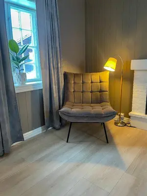 a chair in a room with a lamp and a window at Villa Gulstua in Røros