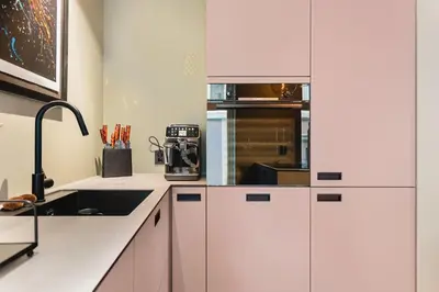 a kitchen with white cabinets and a sink at Bryggen Living in Bergen