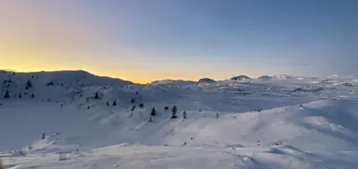a snow covered mountain with a sunset in the background at Delikat hytte omgitt av Hallingdals vakre fjell in Ål
