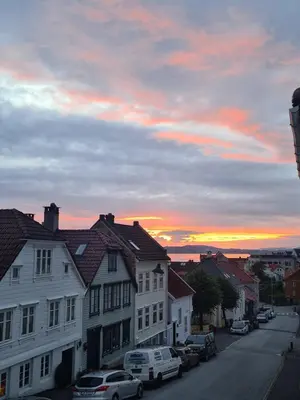 a city street with cars parked in front of a sunset at Fløyen Townhouse in Bergen