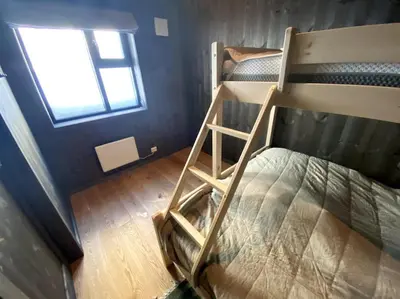 a bunk bed with a ladder in a room with a window at Cosy apartment with ski in/out in Noresund