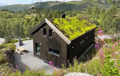 a building with a grassy roof with a bench at Nice Home In Edland With Wifi