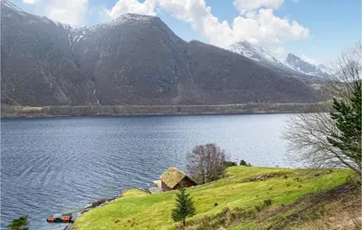 a house on a hill next to a body of water at 2 Bedroom Cozy Home In Lauvstad in Lauvstad