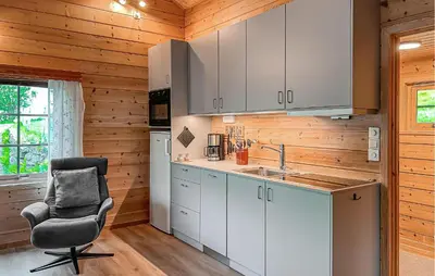 a kitchen with white cabinets and a chair in a room at 2 Bedroom Cozy Home In Lauvstad in Lauvstad