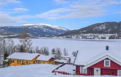 a house in the snow with mountains in the background at Gorgeous Home In Noresund With Wifi in Noresund