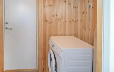 a washer and dryer in a room with a wooden wall at Gorgeous Home In Noresund With Wifi in Noresund