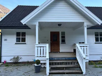 a white house with a porch and a door at Flåm Holiday Home in Flåm