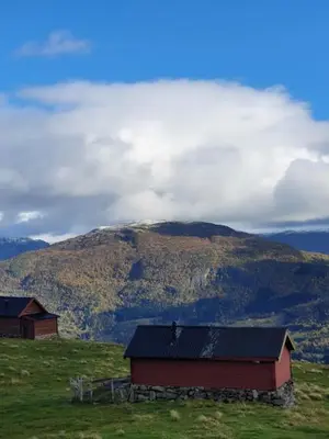 a barn on a hill with a mountain in the background at Molden 1 - med Jacuzzi! in Luster