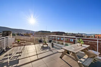 a balcony with a picnic table on top of a building at 2 min to Bryggen - Rooftop - Office with 49