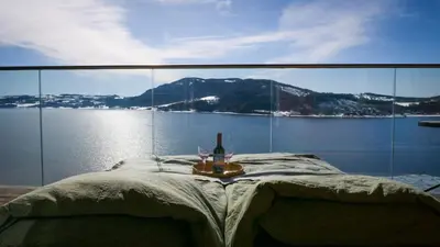 a bed with a bottle of wine and two glasses at MJOS TOWER Suite - Lovely lake view in Brumunddalen